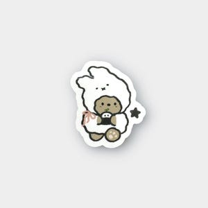 Ours confortable avec sweat à capuche lapin tenant un onigiri | Autocollant en vinyle mat résistant aux intempéries pour ordinateurs portables, bouteilles, journaux, agendas | Animaux mignons