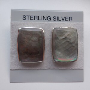 May include: A pair of sterling silver earrings with a rectangular gray mother of pearl inlay.