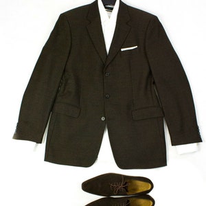Peut inclure: Un blazer marron avec une chemise blanche à col en dessous. Deux chaussures en cuir marron sont placées sous le blazer.