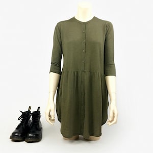 May include: A green button-up dress with 3/4 sleeves. The dress has a relaxed fit and a slightly flared skirt. The dress is on a white mannequin.