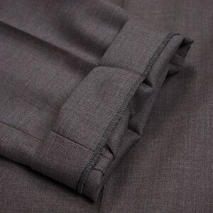 Puede incluir: Primer plano de una tela gris oscura con un pu&ntilde;o doblado. El pu&ntilde;o tiene una costura negra alrededor del borde.