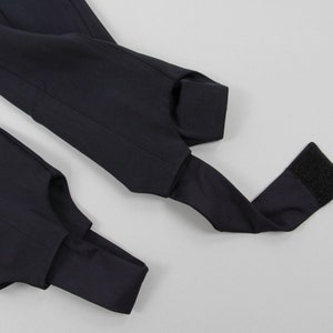 Puede incluir: Primer plano de leggings azul marino con estribos. Los leggings tienen un dise&ntilde;o elegante con una correa de estribo en la parte inferior de cada pierna. La tela parece suave y tiene un ligero brillo. Las correas de estribo est&aacute;n dise&ntilde;adas para ir debajo del pie.