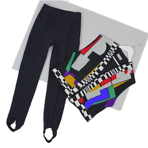 Puede incluir: Un pantal&oacute;n negro con estribo y una blusa sin mangas con un estampado geom&eacute;trico. La blusa presenta una mezcla de colores que incluyen rojo, amarillo, verde y azul, con un dise&ntilde;o a cuadros blanco y negro. El pantal&oacute;n es negro liso.