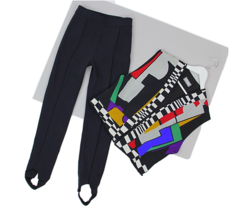 Puede incluir: Un pantal&oacute;n negro con estribo y una blusa sin mangas con un estampado geom&eacute;trico. La blusa presenta una mezcla de colores que incluyen rojo, amarillo, verde y azul, con un dise&ntilde;o a cuadros blanco y negro. El pantal&oacute;n es negro liso.