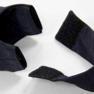 Puede incluir: Una prenda azul marino oscuro con forma curva, con cierre de velcro. La tela parece ser un material liso y mate. El art&iacute;culo se presenta sobre un fondo blanco liso.