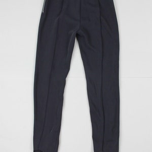 Puede incluir: Pantalones de color azul marino oscuro con estribos y cremallera plateada en el lado izquierdo. Los pantalones tienen cintura alta y costuras verticales en la parte delantera y trasera de las piernas. Los estribos est&aacute;n en la parte inferior.
