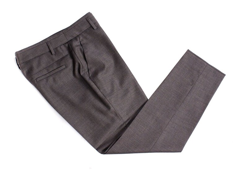 Puede incluir: Un par de pantalones de vestir de color gris oscuro doblados por la mitad. Los pantalones tienen un solo pliegue a cada lado y un bolsillo trasero.