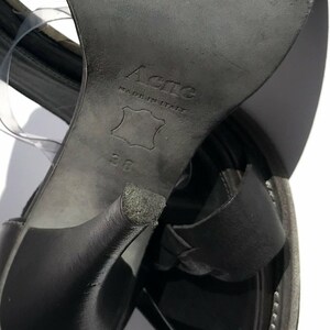 May include: Black leather sandals with a high heel and a buckle closure. The sandals are made in Italy by Acne and are size 38.