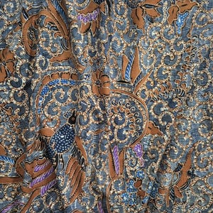 May include: A close-up of a blue and brown fabric with a paisley pattern. The fabric is covered in small, white beads.