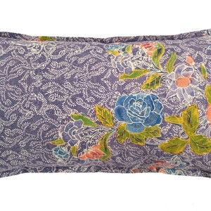 Op de afbeelding: Een paars kussen met een bloemenpatroon met blauwe, gele en roze bloemen. Het kussen heeft een witte achtergrond met een delicaat bloemenpatroon.