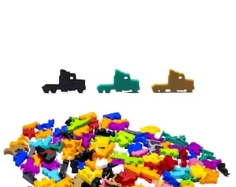 Puede incluir: Un montón de piezas de juego de plástico de colores en varias formas, incluyendo camiones, coches y otros vehículos. Hay tres piezas de camión en el fondo, una negra, una verde y una marrón.