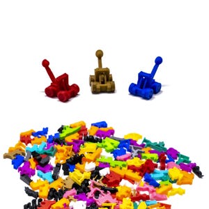 Puede incluir: Un montón de piezas de juguete de plástico de colores con tres catapultas de juguete en el fondo. Las catapultas son rojas, marrones y azules.