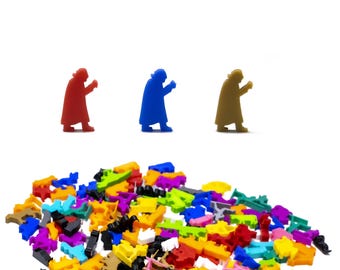 Puede incluir: Tres pequeñas figuritas de personas en rojo, azul y marrón de pie en fila. Un montón grande de piezas de plástico de colores está en primer plano.