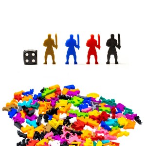 May include: A black six-sided die with white dots, and four plastic figurines of warriors in different colors: gold, blue, red, and black. The figurines are holding swords and are standing on a white surface. A large pile of colorful plastic pieces is in the foreground.