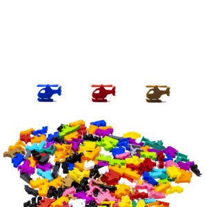 May include: A selection of small, brightly coloured plastic toy pieces, including helicopter shapes and other forms. The helicopters are blue, red, and brown. The other pieces are in a variety of colours, including yellow, green, pink, and black, scattered on a white background.
