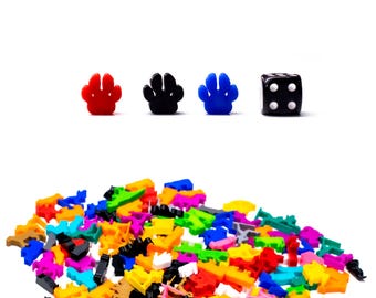 Può includere: Un mucchio di gettoni colorati in plastica a forma di impronta di zampa e un dado nero con punti bianchi. Il dado mostra un quattro.