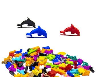 Puede incluir: Un montón grande de figuritas de delfines de plástico de colores vivos. Los delfines son de varios colores, incluyendo rojo, azul, verde, amarillo, naranja y morado. También hay algunos delfines negros en el montón.