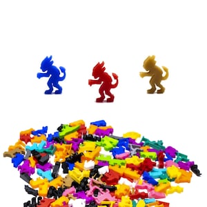 Puede incluir: Un montón de piezas de juego de plástico de colores en varias formas y tamaños. Tres pequeñas figuritas de plástico se muestran encima de la pila: una azul, una roja y una marrón.