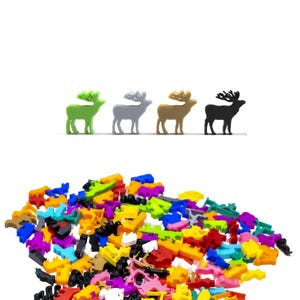 May include: A pile of colourful plastic reindeer figurines in various colours, including green, grey, brown, and black. The reindeer are standing in a row on a white surface.