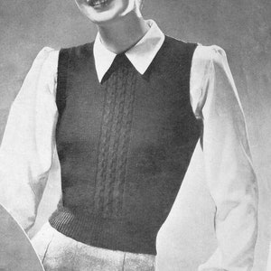 May include: A black and white photograph of a woman wearing a white collared shirt with a black knitted waistcoat. The waistcoat has a cable knit pattern and a V-neck.