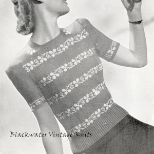 May include: A vintage knitting pattern for a women's sweater with a white floral design on a dark background. The pattern is called "Blackwater Vintage Knits".