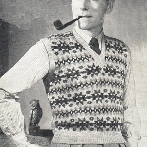 May include: A black and white patterned knitted vest with a V-neck. The vest is worn over a white button-down shirt with a dark tie. The person is holding a pipe in their mouth.