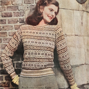 May include: A woman wearing a brown, white, and yellow patterned sweater with a brown, white, and yellow striped band at the bottom. The sweater has a crew neck and long sleeves. The woman is standing in front of a brick wall.