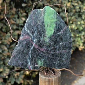 Peut inclure: Une pierre verte, noire et blanche à la texture rugueuse est montée sur un poteau en bois avec du fil de cuivre.