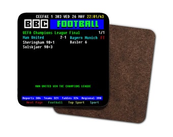 May include: A square coaster with a black background displaying BBC Football scores from the UEFA Champions League Final. The text includes the date, time, and scores for Man United vs. Bayern Munich. A second, brown coaster is partially visible.