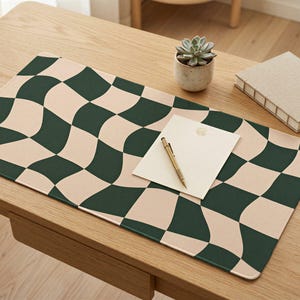 May include: A rectangular desk mat featuring a wavy, distorted checkerboard pattern in dark forest green and cream. The mat has rounded corners and a smooth, flat surface, providing a large area for workspace organisation and desk protection.