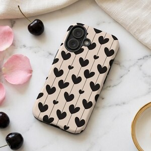 May include: A beige smartphone case featuring a repeating pattern of black hearts connected by thin vertical lines. The case has a black camera lens cutout at the top left corner and a smooth, matte finish covering the back and sides of the device.