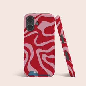 Puede incluir: Una funda de teléfono roja y rosa con un patrón ondulado. La funda se muestra con una funda de teléfono a juego apoyada contra ella. La funda del teléfono tiene una cámara y una ranura para tarjetas azul.