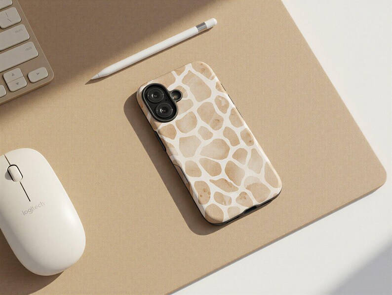 May include: A smartphone case with a giraffe print design in shades of beige and white. The case is lying on a tan surface next to a white mouse, a white pencil, and a keyboard.