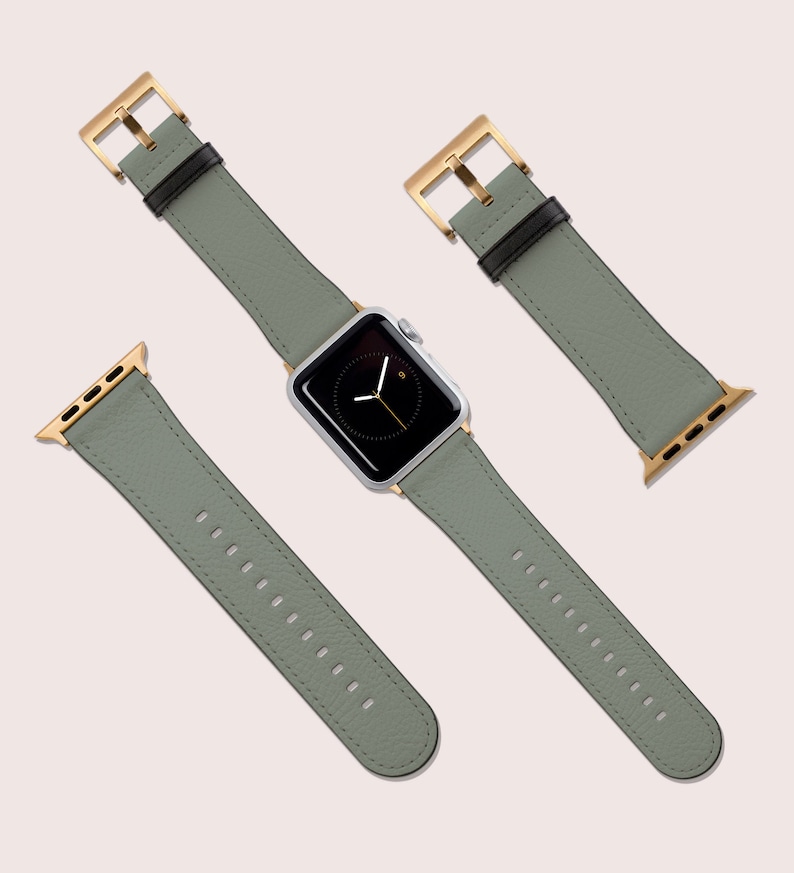May include: A sage green leather watch band with gold hardware. The band is shown in three different positions: on a watch, with the buckle closed, and with the buckle open.