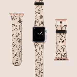May include: A beige Apple Watch band with a black and white abstract face design. The band is shown on a white background.