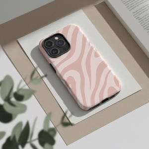 May include: A pink and white swirled pattern phone case. The case is made of a hard plastic and has a glossy finish. The phone case is designed to fit a smartphone and has cutouts for the camera and buttons.