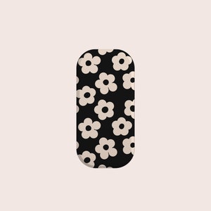 Pode incluir: Uma caixa retangular preta e branca com um padrão floral. A caixa tem bordas arredondadas e um fundo branco com flores pretas.