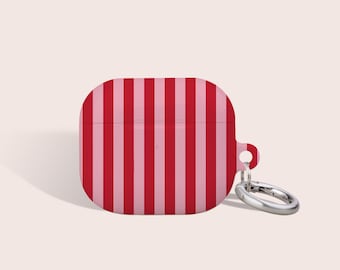 May include: A protective silicone case for wireless earbuds featuring a vertical striped pattern in alternating shades of bright red and light pink. The case includes a small side loop with a silver-toned metal ring attached for hanging.