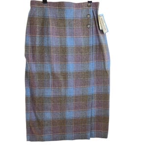 May include: A Pendleton brand midi-length skirt featuring a blue, brown, and purple plaid pattern. The skirt has a wrap-style front closure secured by three round buttons along the side and includes an attached paper brand tag.