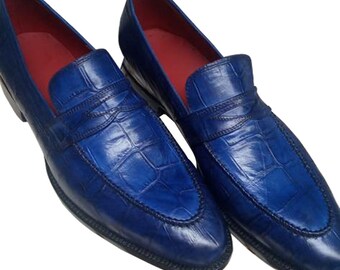 May include: A pair of blue leather loafers with a crocodile pattern. The loafers have a pointed toe and a slip-on design.