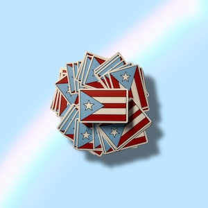 May include: A collection of stickers featuring the flag of Puerto Rico. Each sticker has a red and white striped section, a blue triangle with a white star, and a white border. The stickers are arranged on a light blue background.