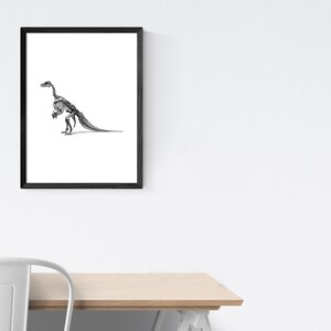 May include: Black and white illustration of a dinosaur skeleton in a black frame.