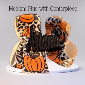 May include: A medium-sized hair bow with a leopard print and orange pumpkins. The bow has a black glitter name tag that says "Ariana" in a cursive font.