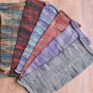 May include: A set of seven colorful striped leg warmers made of knitted fabric. The leg warmers are arranged in a fan shape, with the gray leg warmer at the bottom.