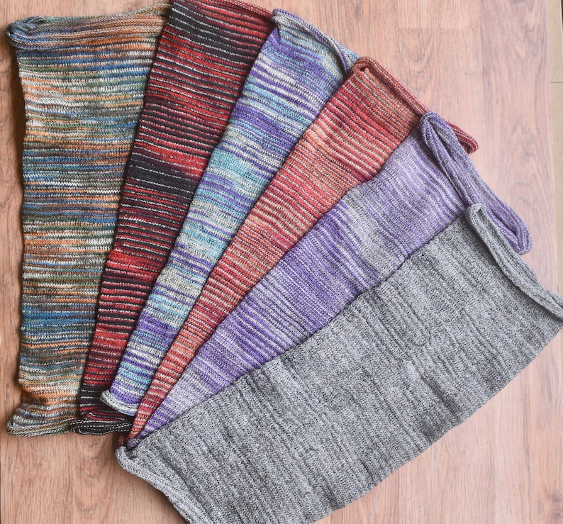 May include: A set of seven colorful striped leg warmers made of knitted fabric. The leg warmers are arranged in a fan shape, with the gray leg warmer at the bottom.