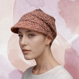 May include: A brown crochet newsboy cap with a wide brim. The cap is made of a delicate, open-weave fabric.