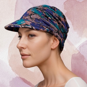 May include: A patterned fabric hat with a visor. The hat is blue, green, and pink with a floral design.
