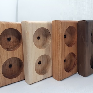 May include: Four wooden holders with two circular cutouts each. The holders are made of different types of wood, including light wood, medium brown wood, and dark brown wood.