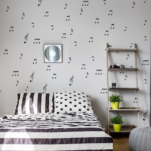 May include: A bedroom with a black and white striped bedspread, a grey pouf, and a guitar leaning against a chalkboard wall with music notes and the words "The Dance Never Dies" written on it.