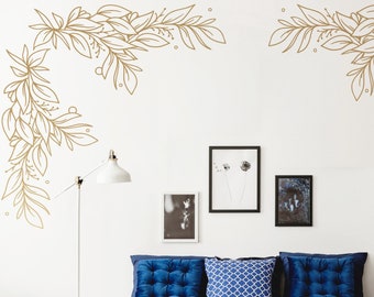 May include: A blue bed with a gray throw blanket and a wicker tote bag. The bed has three blue pillows, one with a geometric pattern. The wall behind the bed has a gold leaf design in the corners.